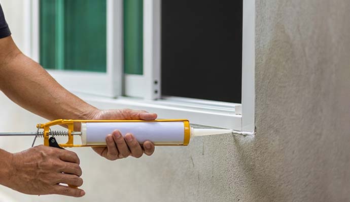 A person sealing a window frame