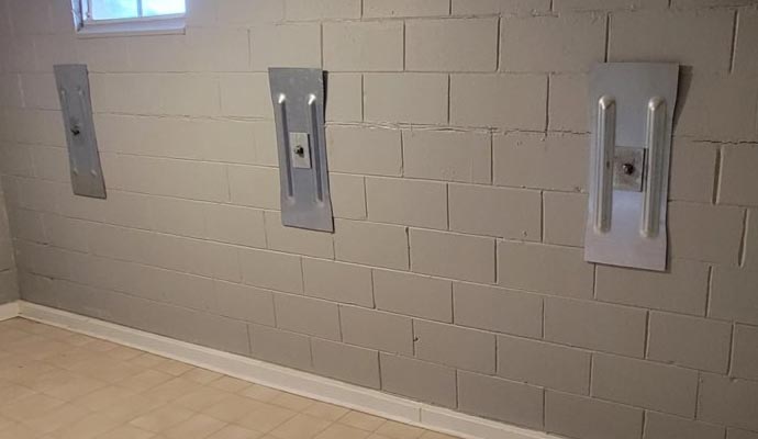 Basement wall with three steel wall anchors installed to reinforce and stabilize the foundation