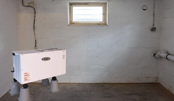 Dehumidifier unit installed in a residential basement to control humidity and moisture