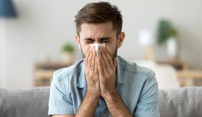 Man sneezing due to an allergic reaction