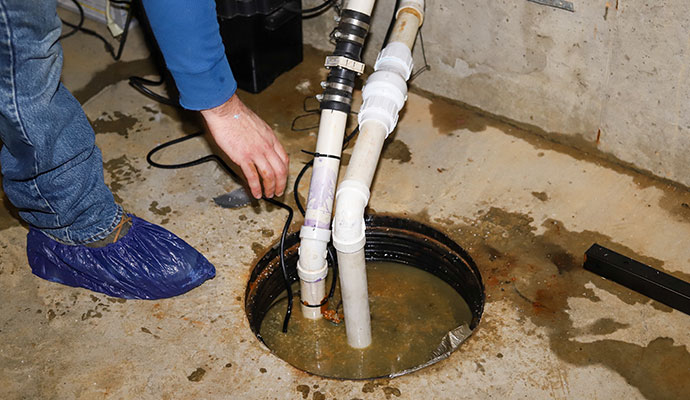 plumber repairing a sump pump in flooded basement